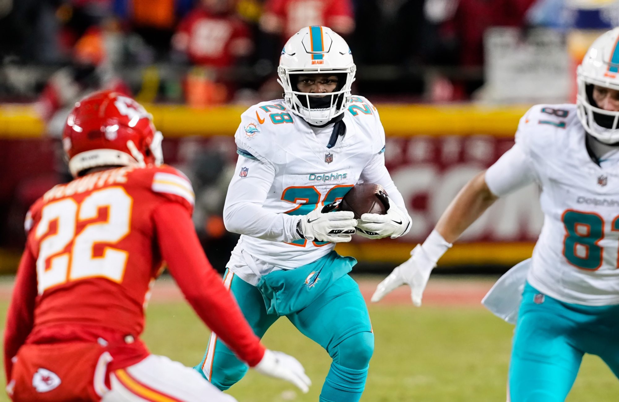 Jan 13, 2024; Kansas City, Missouri, USA; Miami Dolphins running back De'Von Achane (28) runs the ball against Kansas City Chiefs cornerback Trent McDuffie (22) during the second half of a 2024 AFC wild card game at GEHA Field at Arrowhead Stadium.