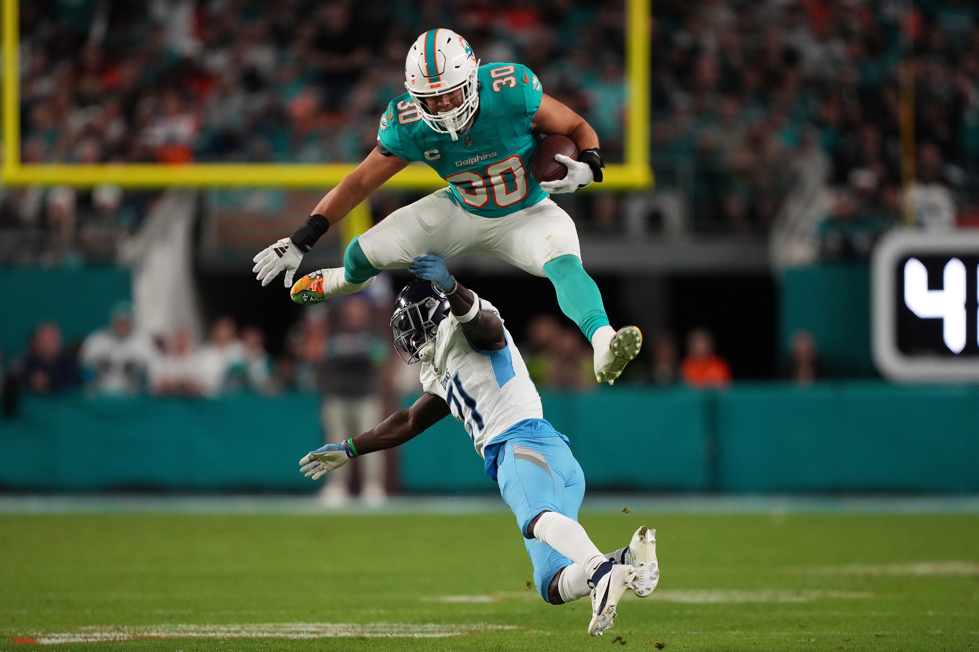 Dec 11, 2023; Miami Gardens, Florida, USA; Miami Dolphins fullback Alec Ingold (30) leaps over Tennessee Titans cornerback Roger McCreary (21) during the second half at Hard Rock Stadium.