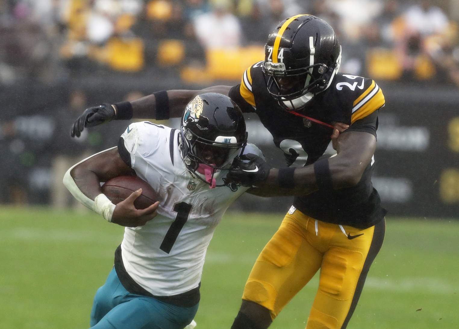 Oct 29, 2023; Pittsburgh, Pennsylvania, USA; Jacksonville Jaguars running back Travis Etienne Jr. (1) carries the ball as Pittsburgh Steelers cornerback Joey Porter Jr. (24) commits a face-mask penalty during the first quarter at Acrisure Stadium.