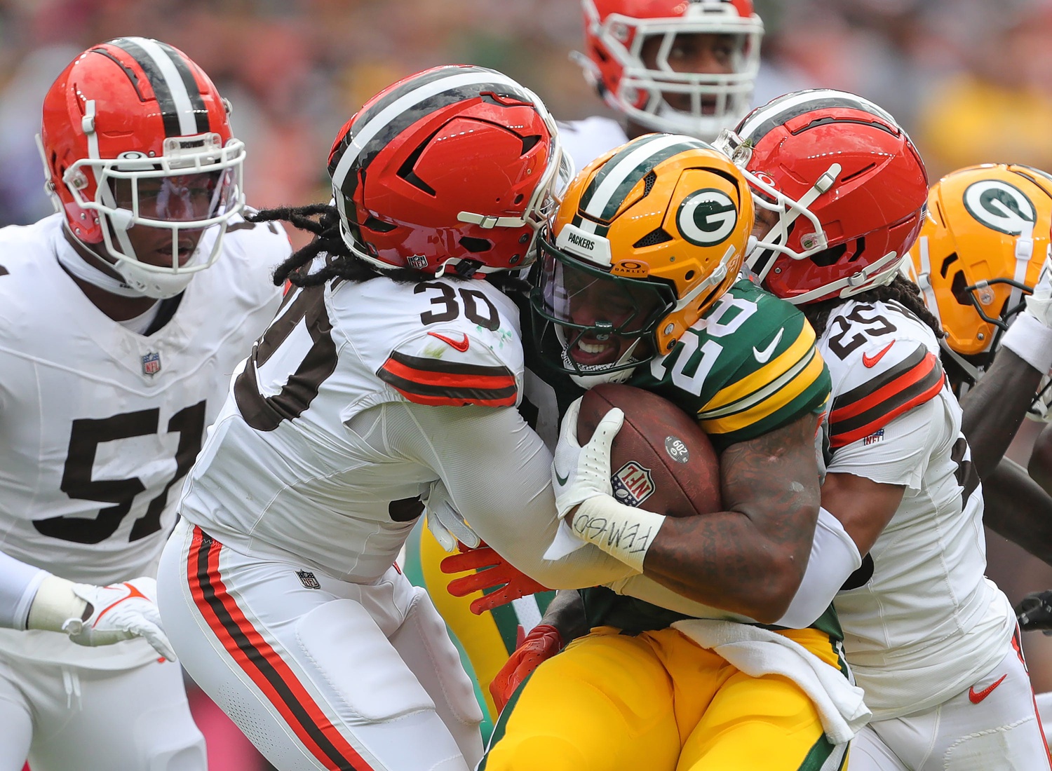 Green Bay Packers running back AJ Dillon (28) is sandwiched between Cleveland Browns linebacker Devin Bush (30) and Cleveland Browns cornerback Kahlef Hailassie (25) during the first half of an NFL preseason football game at Cleveland Browns Stadium, Saturday, Aug. 10, 2024, in Cleveland, Ohio.