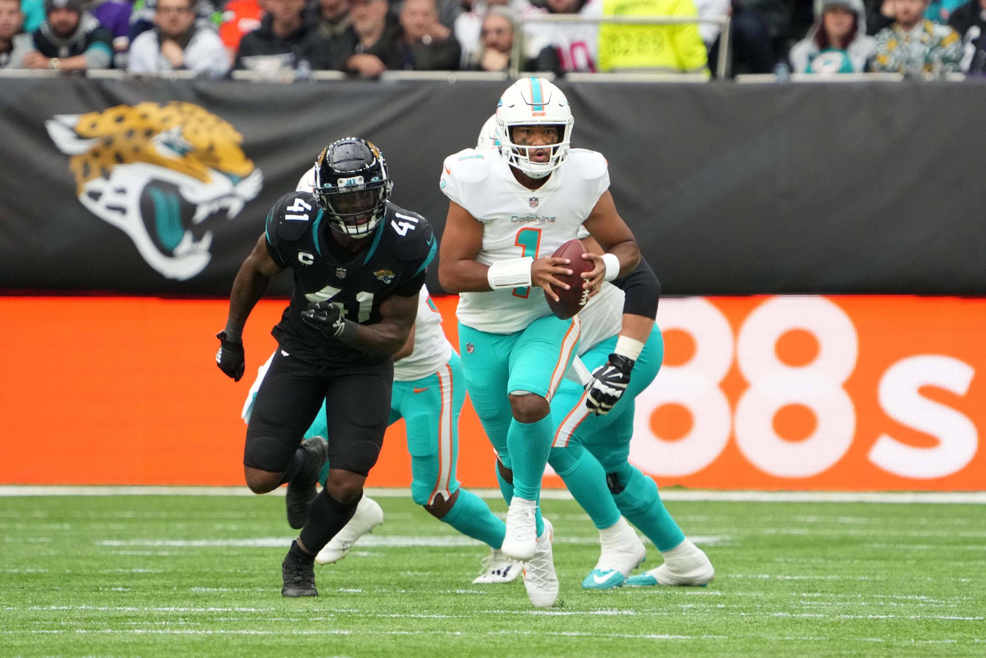 Oct 17, 2021; London, England, United Kingdom; Miami Dolphins quarterback Tua Tagovailoa (1) is pursued by Jacksonville Jaguars outside linebacker Josh Allen (41) in the second half during an NFL International Series game at Tottenham Hotspur Stadium. The Jaguars defeated the Dolphins 23-20.