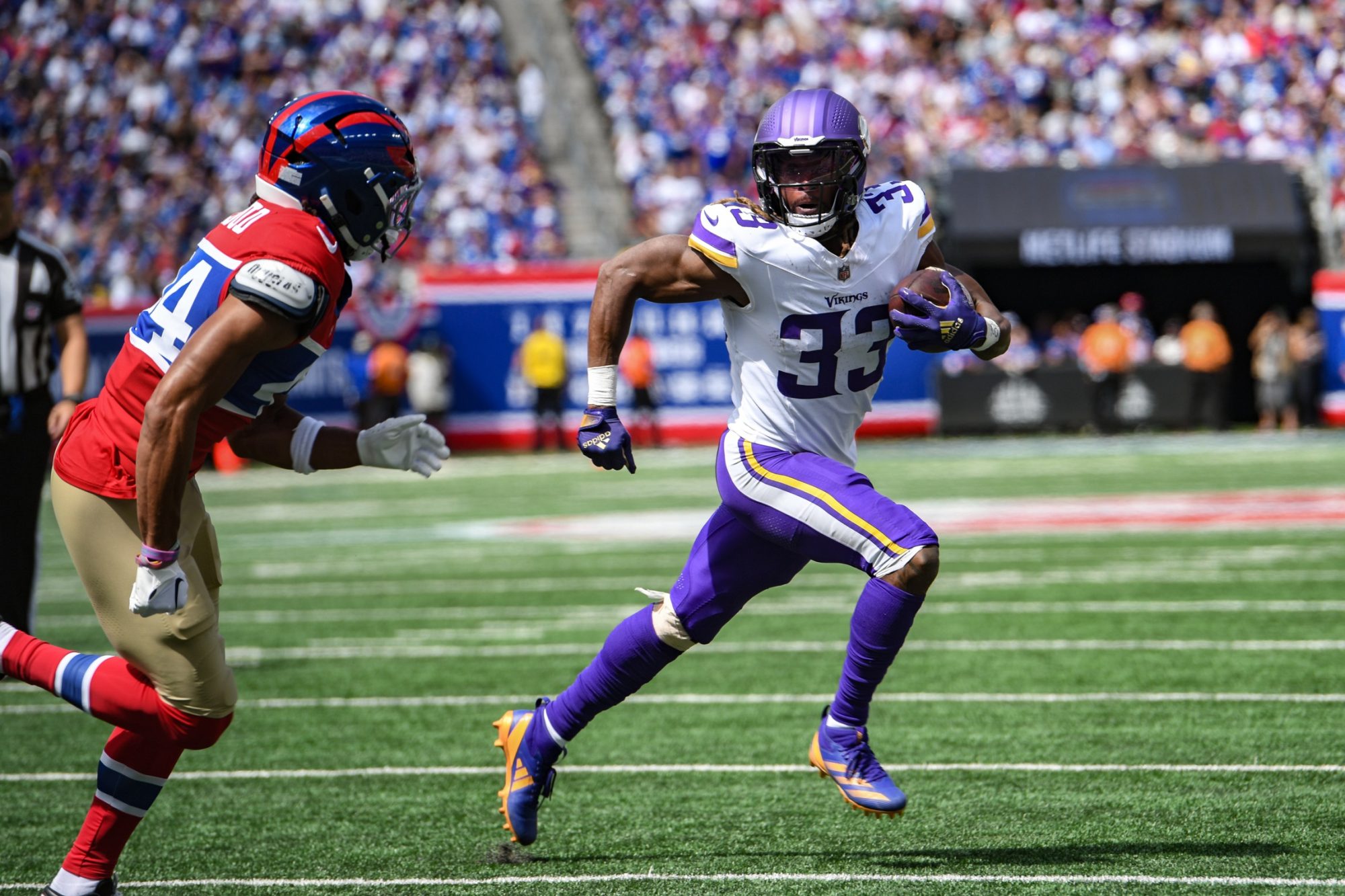 Sep 8, 2024; East Rutherford, New Jersey, USA; Minnesota Vikings running back Aaron Jones (33) runs for a touchdown as New York Giants cornerback Nick McCloud (44) defends during the first half at MetLife Stadium.