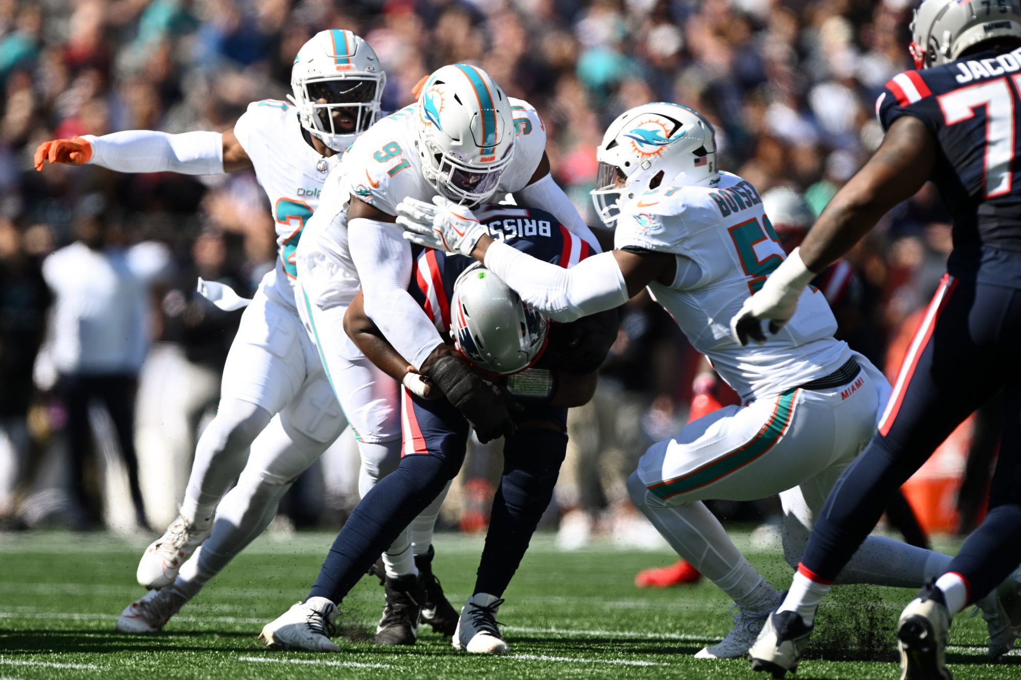 Oct 6, 2024; Foxborough, Massachusetts, USA; New England Patriots quarterback Jacoby Brissett (7) is sacked by linebacker Jordyn Brooks (20), linebacker Emmanuel Ogbah (91), and linebacker Tyus Bowser (51) during the first half at Gillette Stadium.