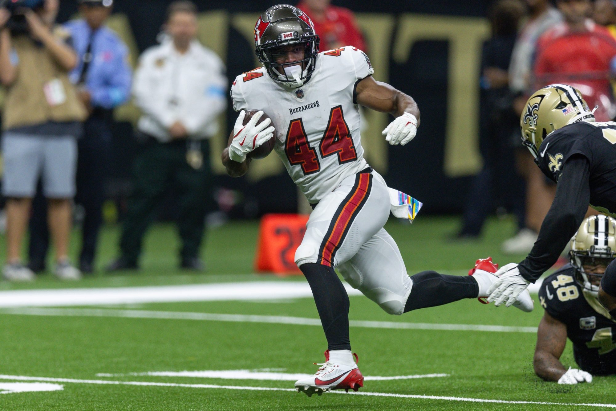 Oct 13, 2024; New Orleans, Louisiana, USA; Tampa Bay Buccaneers running back Sean Tucker (44) runs away from the tackle of New Orleans Saints safety J.T. Gray (48) during the first half at Caesars Superdome.