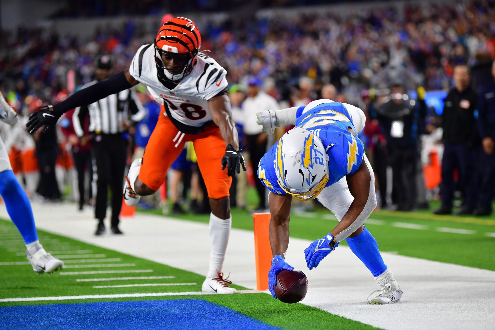 Nov 17, 2024; Inglewood, California, USA; Los Angeles Chargers running back J.K. Dobbins (27) scores a touchdown against Cincinnati Bengals cornerback Josh Newton (28) during the second half at SoFi Stadium.