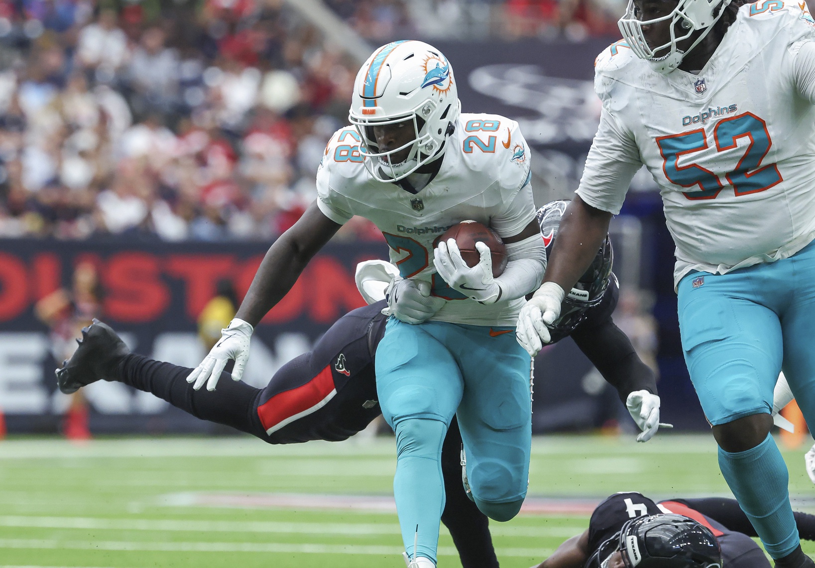 Dec 15, 2024; Houston, Texas, USA; Miami Dolphins running back De'Von Achane (28) runs with the ball as Houston Texans linebacker Christian Harris (48) attempts to make a tackle during the second quarter at NRG Stadium.