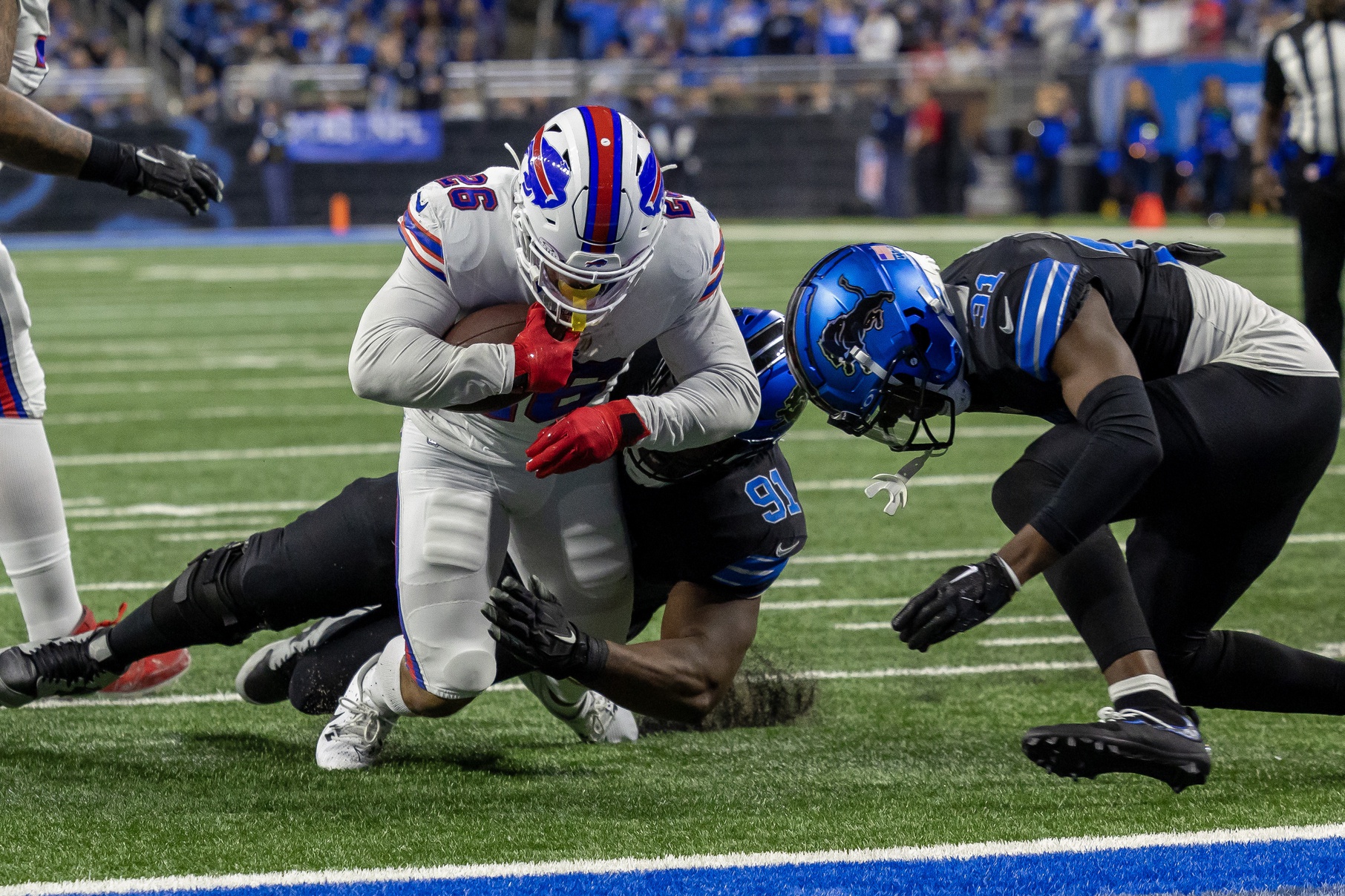 Dec 15, 2024; Detroit, Michigan, USA; Buffalo Bills running back Ty Johnson (26) is tackled by Detroit Lions defensive end Levi Onwuzurike (91) and safety Kerby Joseph (31) during the first quarter at Ford Field.