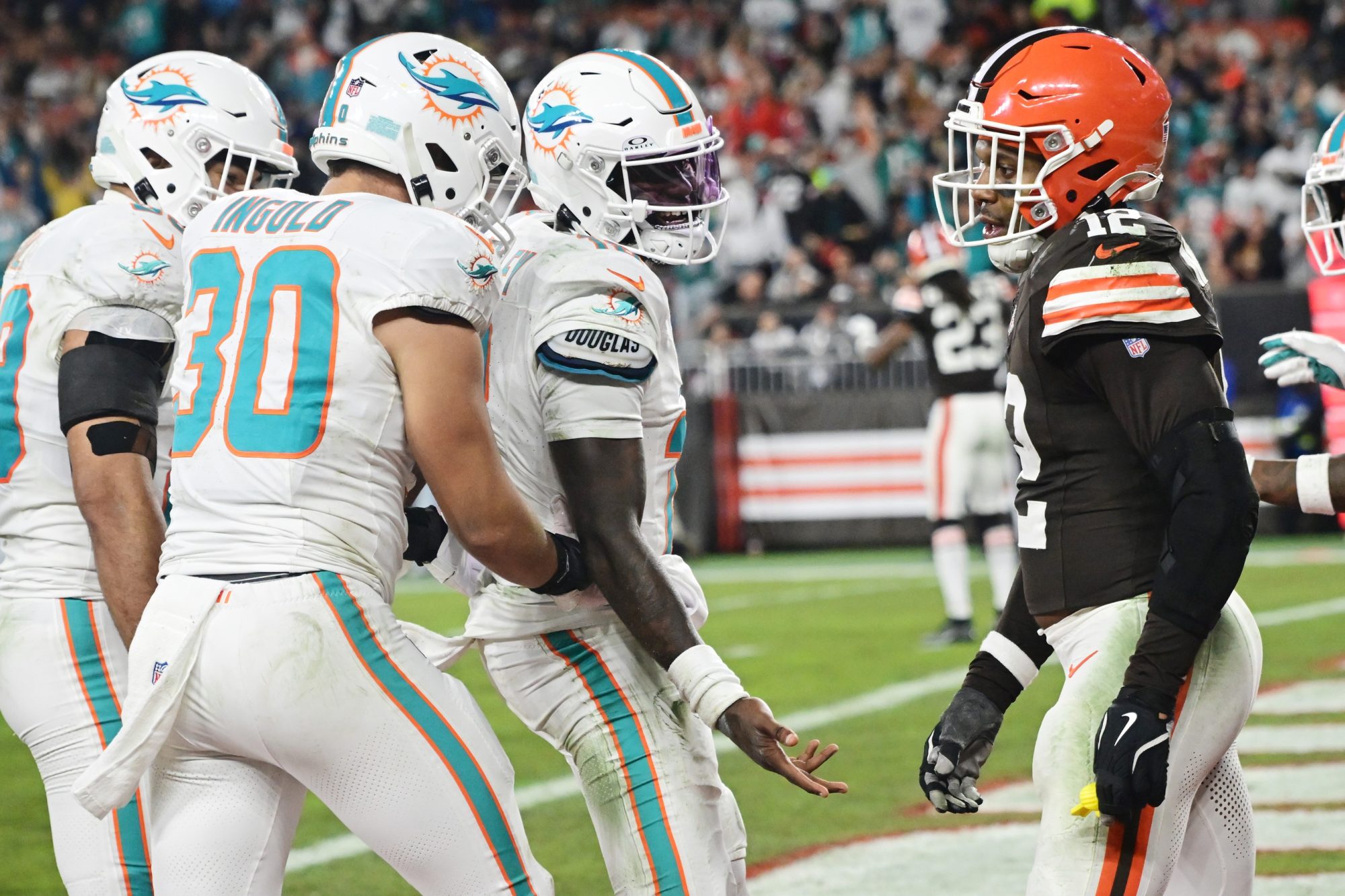 Dec 29, 2024; Cleveland, Ohio, USA; Miami Dolphins quarterback Tyler Huntley (18) celebrates with fullback Alec Ingold (30) after scoring a touchdown as Cleveland Browns safety Rodney McLeod Jr. (12) looks on during the second half at Huntington Bank Field.